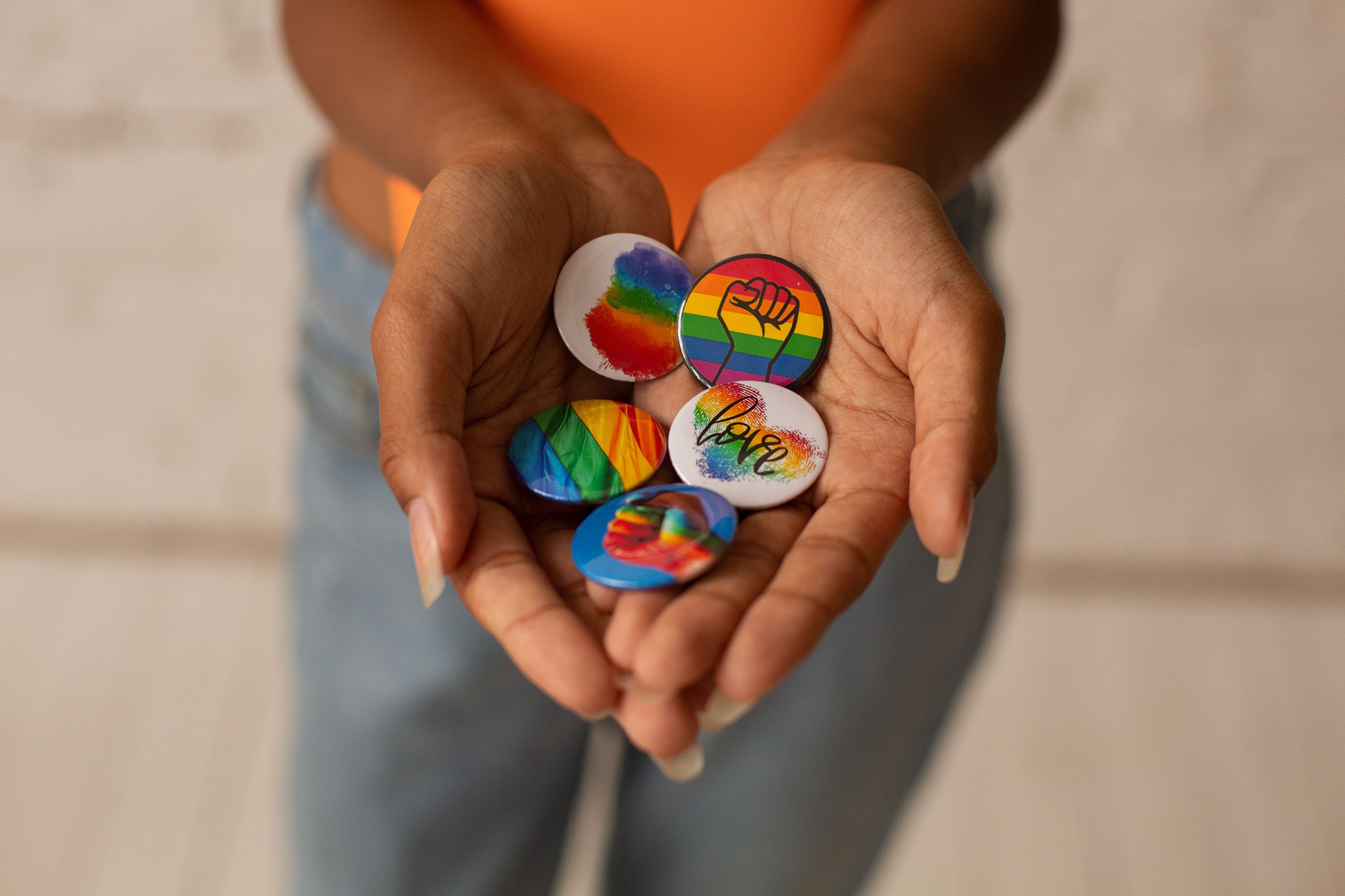 手中捧着彩虹与 Pride 图案徽章
